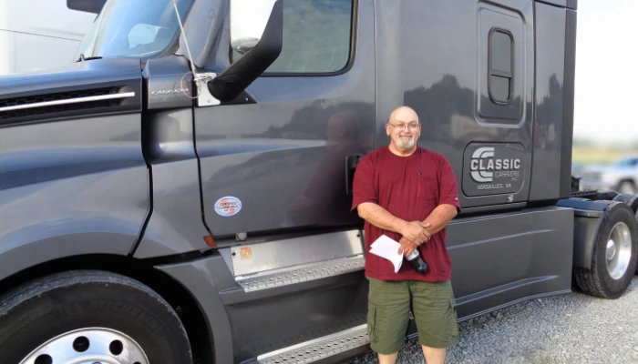 Driver with paperwork standing beside a Classic Carriers truck